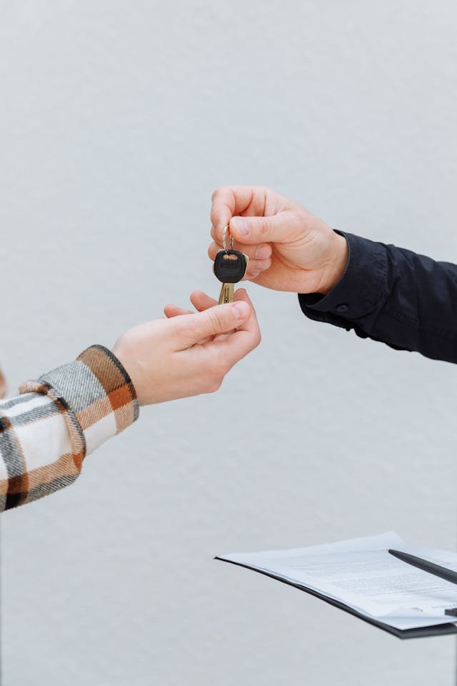 Person handing car keys to another person during a vehicle rental transaction
