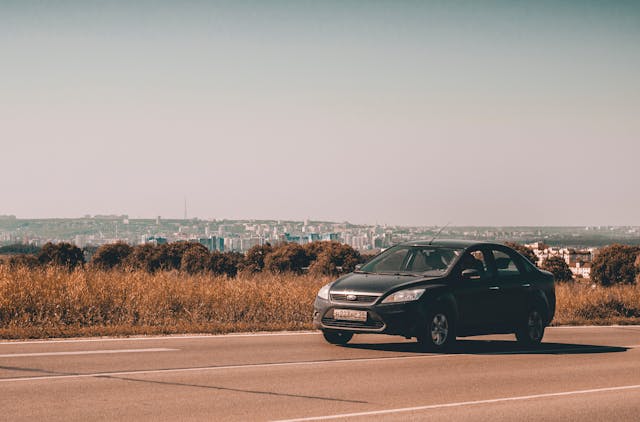 an economy car driving past a city
