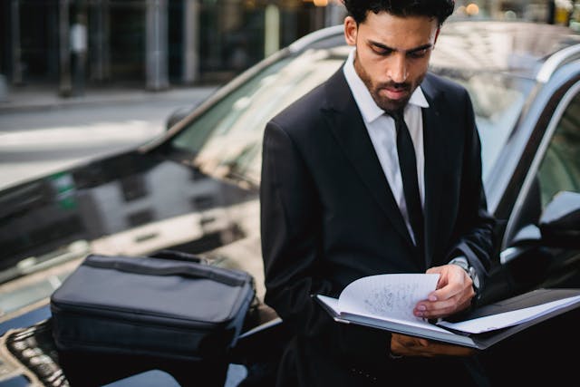 business man looking through notes on hood of business rental car in los angeles