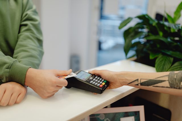 two hands running a debit or credit card