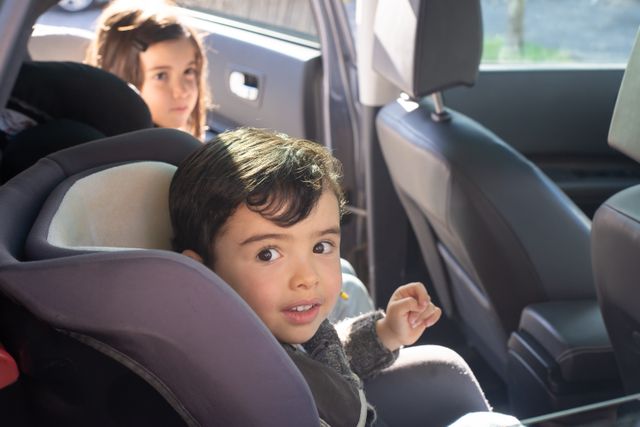 two children in car seats in the back of a car